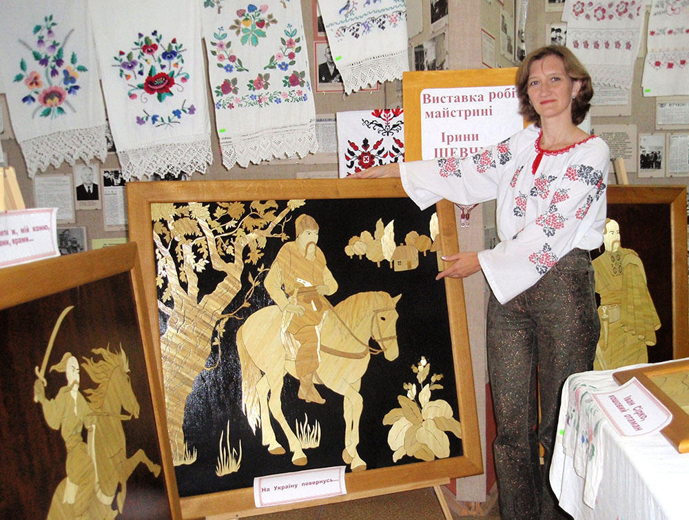 Майстриня І. Шевчук біля своїх картин із соломки